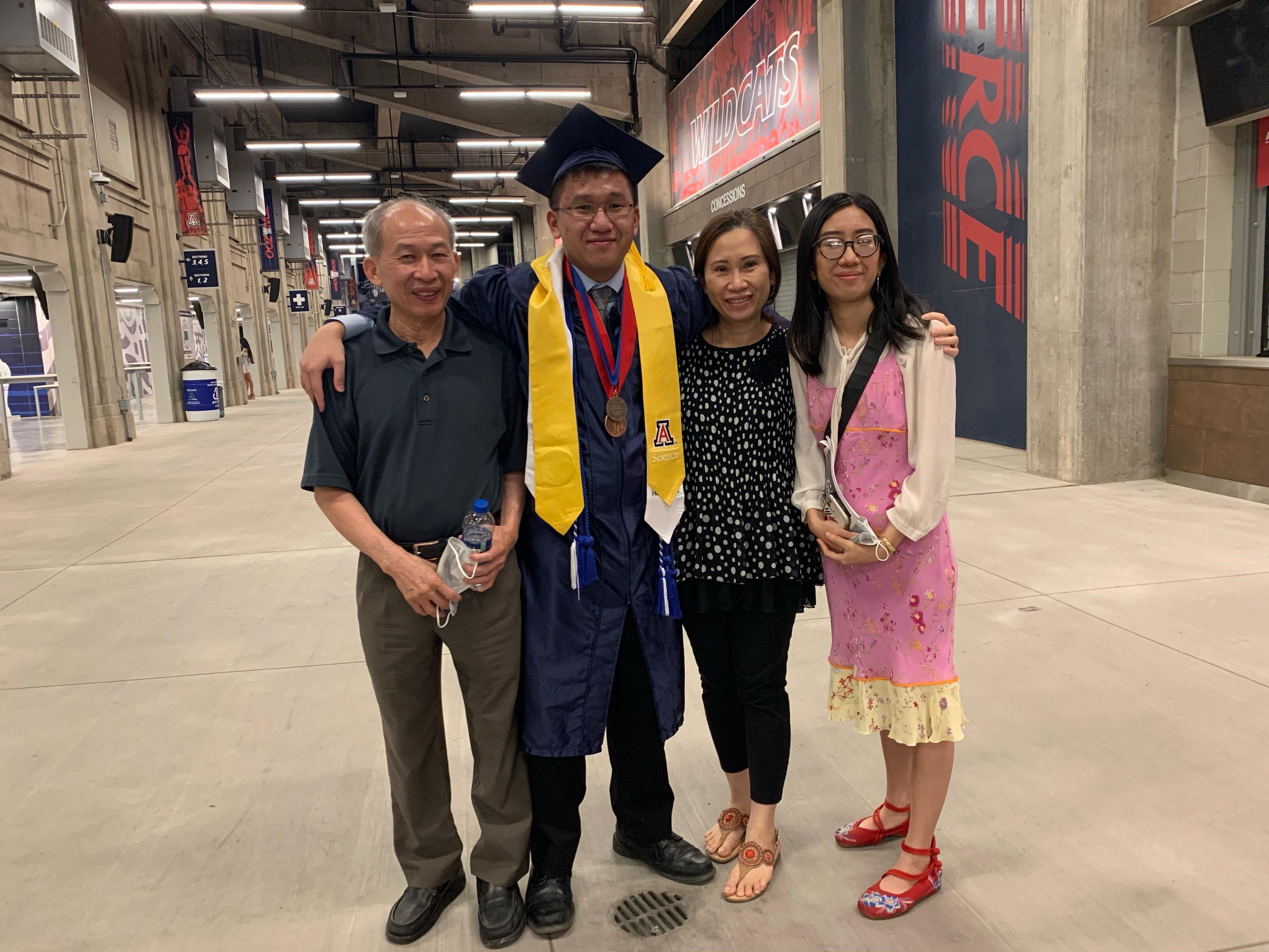 Ryan in cap and gown with his parents and sister at the University of Arizona graduation