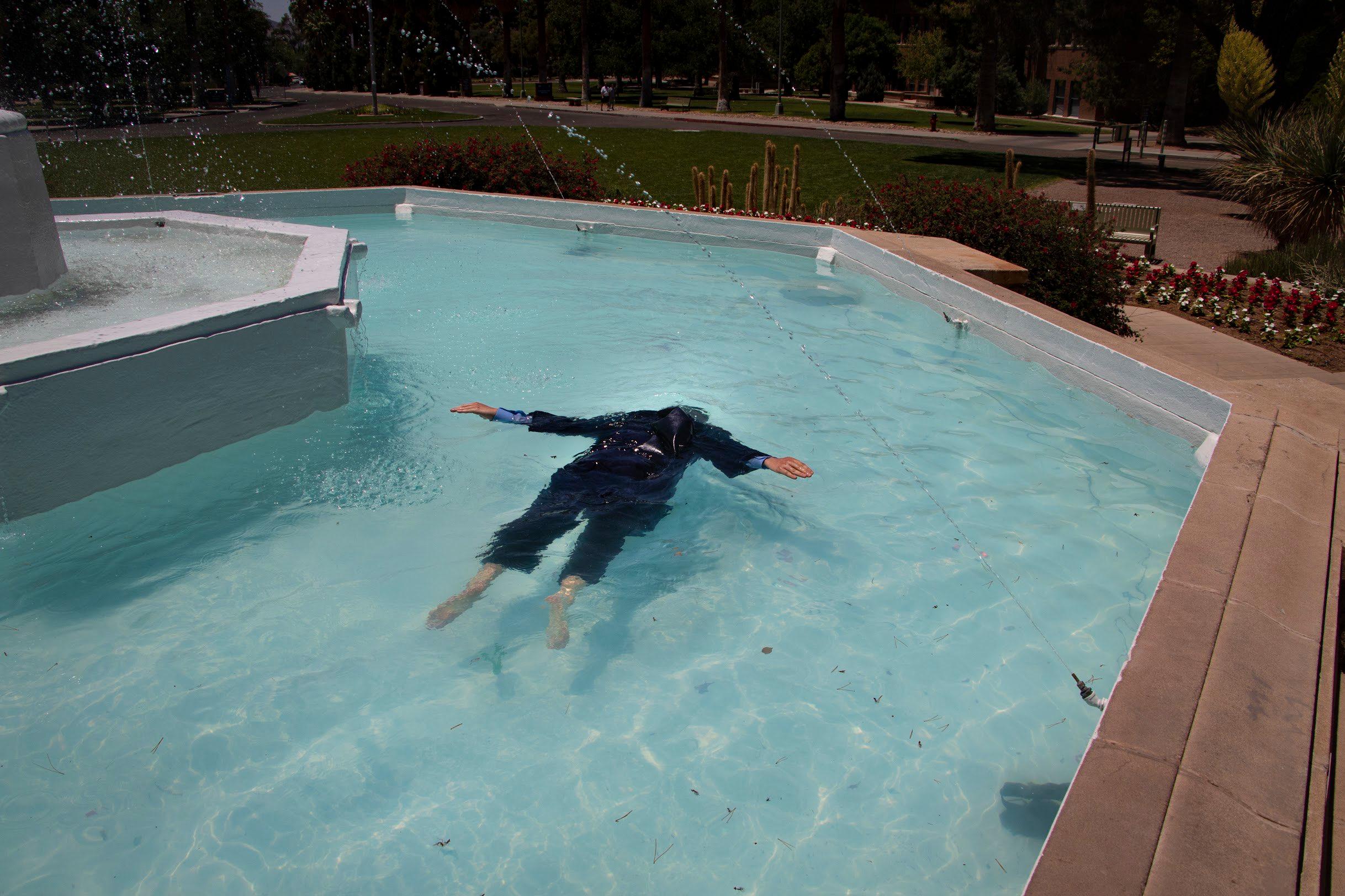 Ryan floating face-down in the Old Main fountain in his graduation gown
